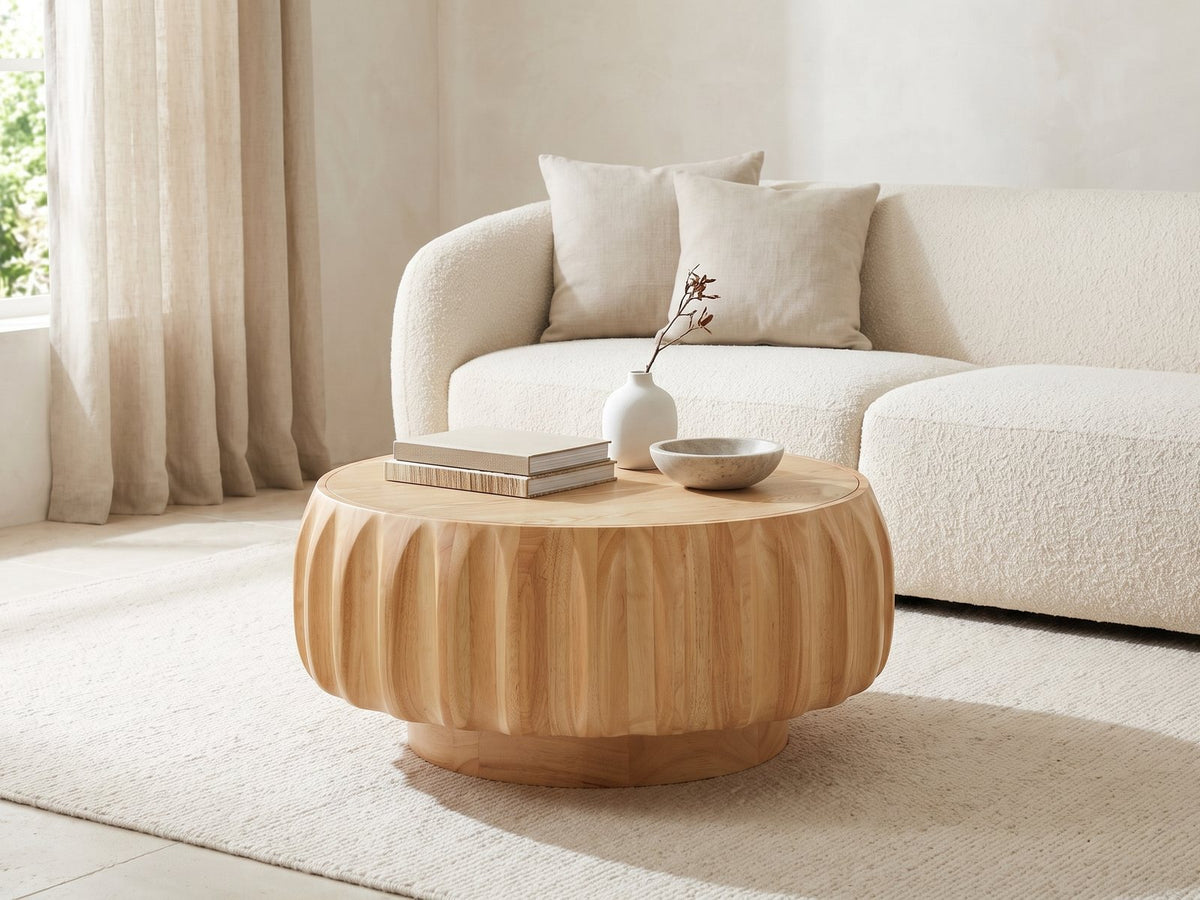 Montepulciano Fluted Ash Coffee Table styled with books, a vase and a stone bowl in front of a cream sofa in a bright plaster room