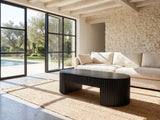 Monterosso Black Wood Veneer Fluted Oval Coffee Table on a jute rug in front of a linen sofa in a poolside villa