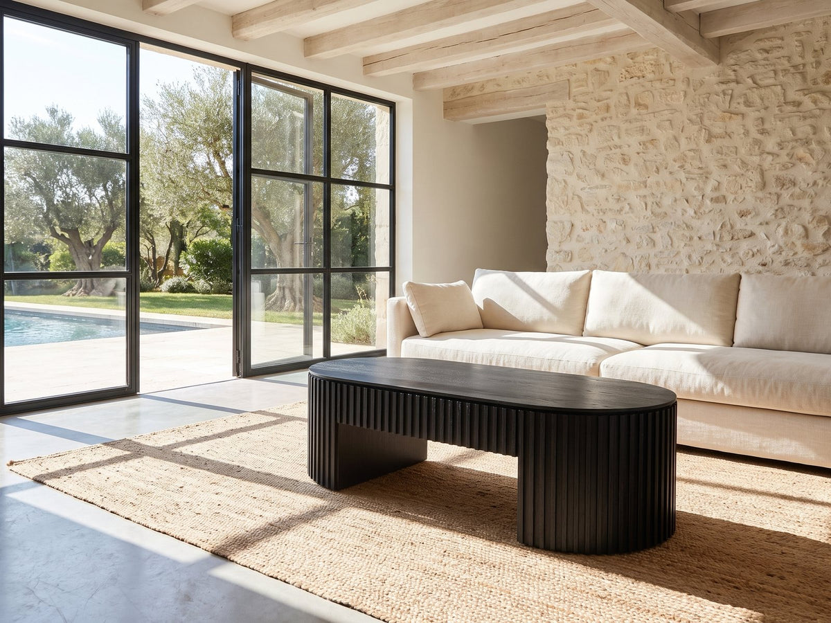 Monterosso Black Wood Veneer Fluted Oval Coffee Table on a jute rug in front of a linen sofa in a poolside villa