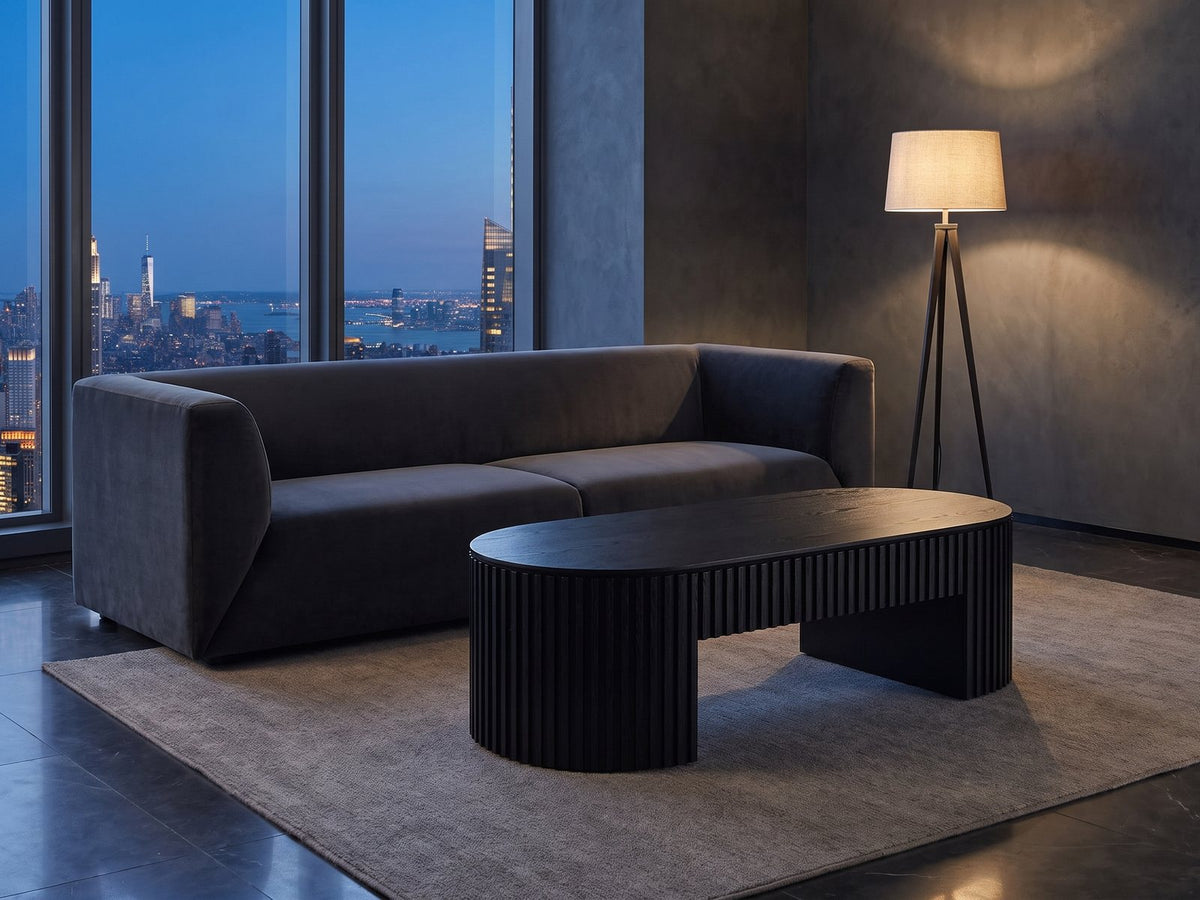 Monterosso Black Wood Veneer Fluted Oval Coffee Table on a wool rug in front of a velvet sofa in a city penthouse at blue hour