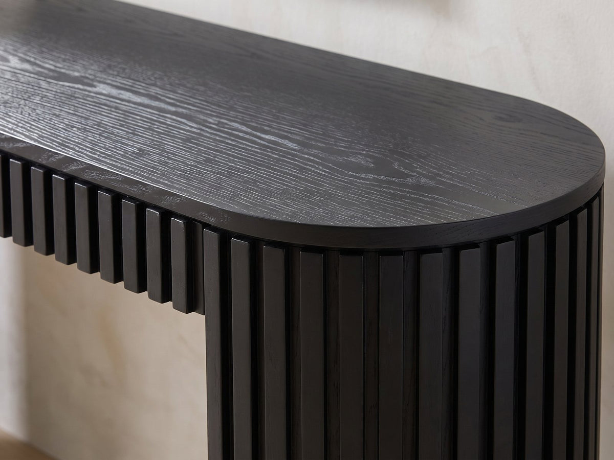 Close-up of the Monterosso Black Wood Veneer Fluted Oval Console Table: the thin black top over the slatted apron and a slatted end