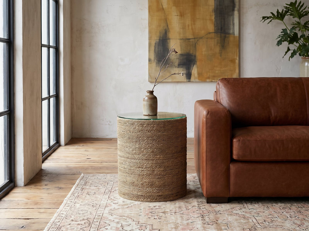 Montescaglioso Woven Seagrass Drum Side Table beside a leather sofa in an industrial loft