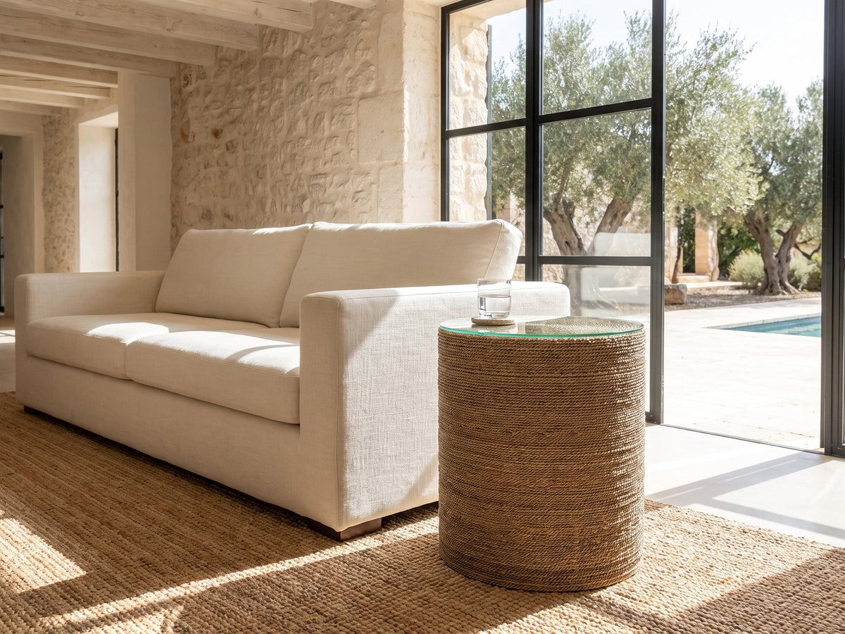 Montescaglioso Woven Seagrass Drum Side Table beside a linen sofa in a poolside villa