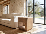 Monticchiello Driftwood Oak Veneer Cube Side Table beside a linen sofa in a poolside villa