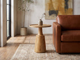 Montisi Natural Mango Pedestal Side Table beside a leather sofa in an industrial loft