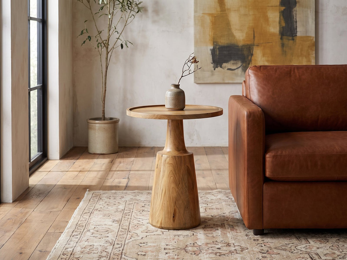 Montisi Natural Mango Pedestal Side Table beside a leather sofa in an industrial loft