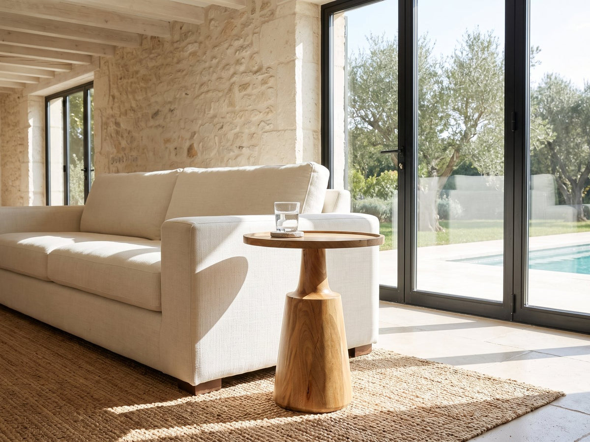 Montisi Natural Mango Pedestal Side Table beside a linen sofa in a poolside villa