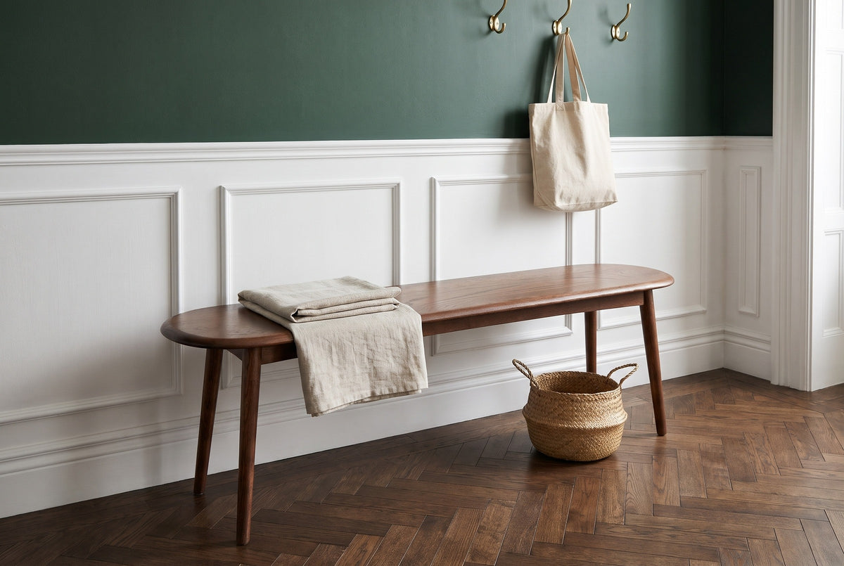 Montone bench in a Brooklyn brownstone entry hall with a deep green wall, white wainscot panelling, a herringbone floor and a seagrass basket