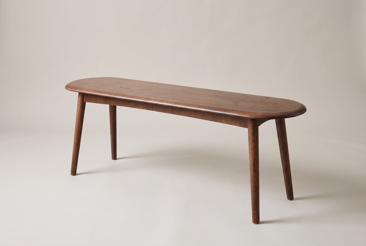 The Montone walnut-stained oak bench, three-quarter view on a light studio backdrop