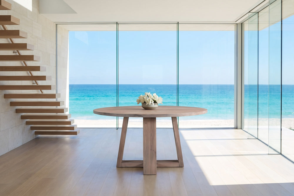 Morano 54-Inch Round Grey-Washed Solid Acacia Dining Table in an oceanfront glass house