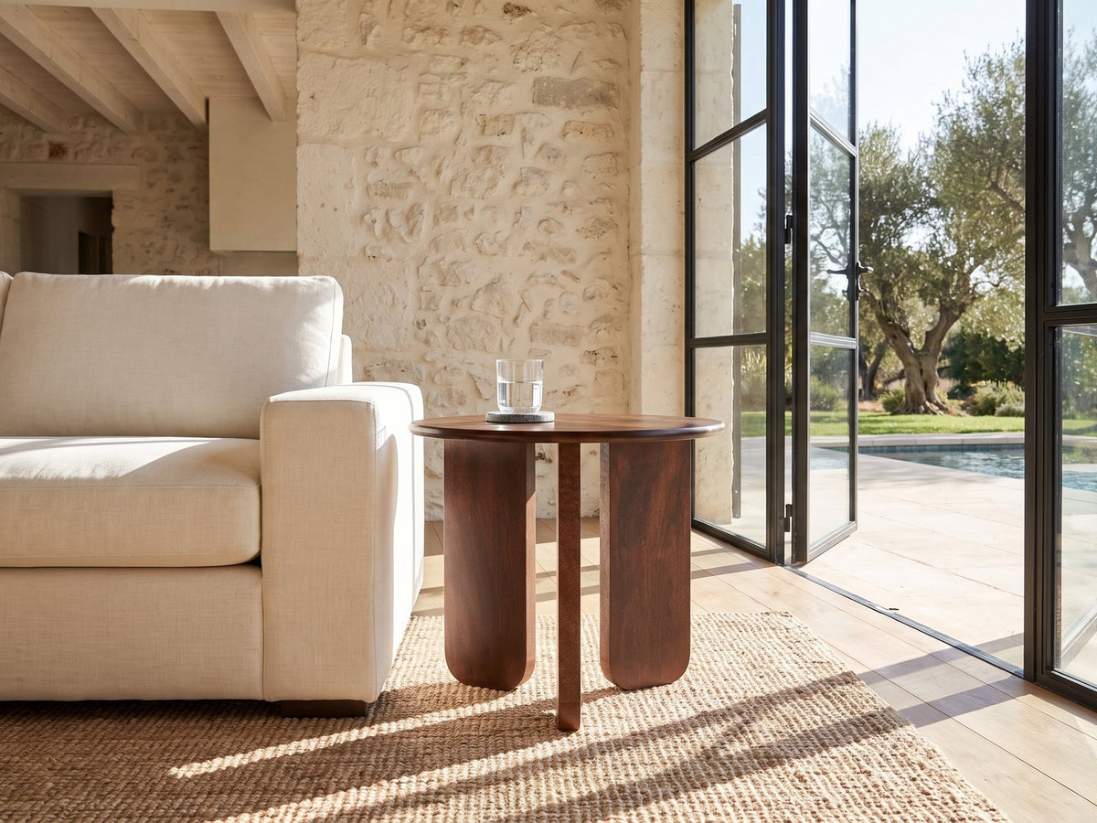 Morciano Mango Wood Round Side Table beside a linen sofa in a poolside villa