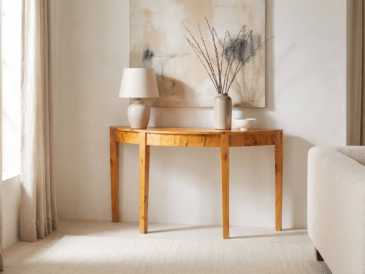 Mottola Mappa Burl Half-Moon Console Table against a plaster wall under an abstract canvas in a bright living room
