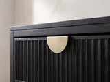 Close-up of the Murano 66-Inch Black Oak 8-Drawer Dresser with Mirror: a brushed antique-gold half-moon pull at the top edge of a reeded black oak drawer