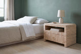 Muravera grasscloth one-drawer nightstand with a ceramic lamp beside a low bed in a Portland bedroom with a deep sage-green plaster wall and a pale ash floor