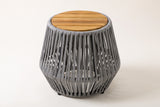 The Naro side table, three-quarter view: a round slatted acacia top over a flared grey rope body, on a light studio backdrop