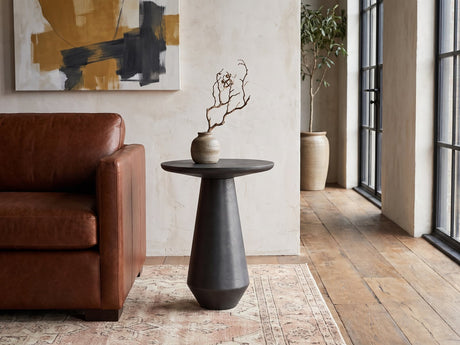 Navelli Graphite Cast Aluminum Pedestal Side Table beside a leather sofa in an industrial loft