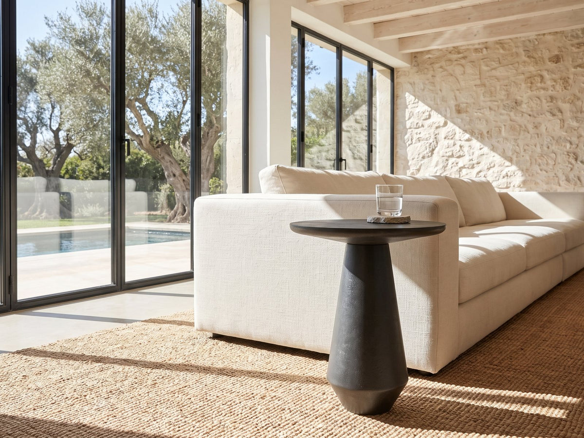 Navelli Graphite Cast Aluminum Pedestal Side Table beside a linen sofa in a poolside villa
