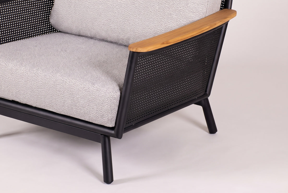 One corner of a Naxos chair: the light grey seat cushion, the black seat and base rails, the perforated side and two slim tapered legs