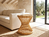 Neviano Natural Rattan Hourglass Side Table beside a linen sofa in a poolside villa