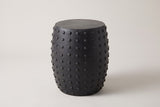 The Nicolosi matte black studded concrete side table, three-quarter view on a light studio backdrop