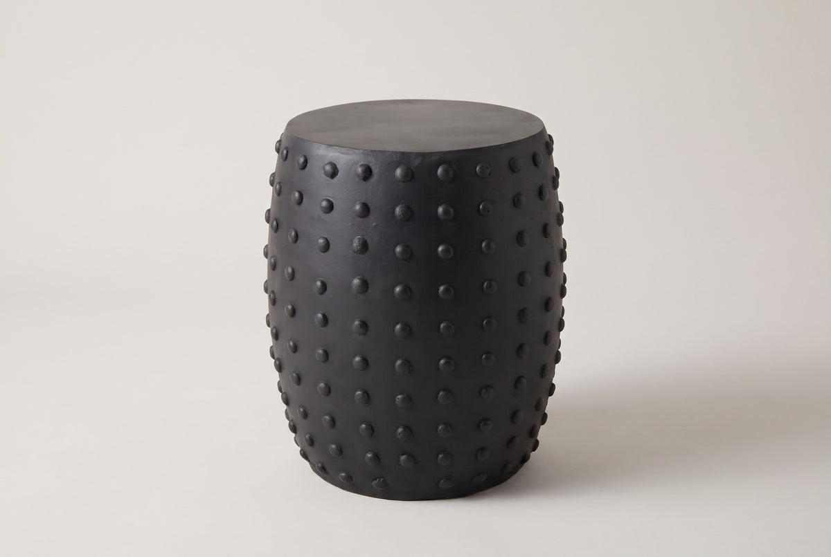The Nicolosi matte black studded concrete side table, three-quarter view on a light studio backdrop