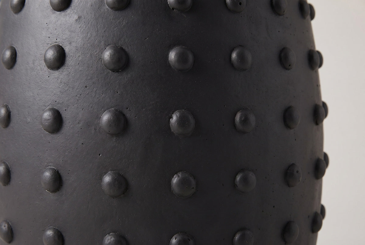 Close-up of the matte black lightweight concrete and the round studs on the Nicolosi side table