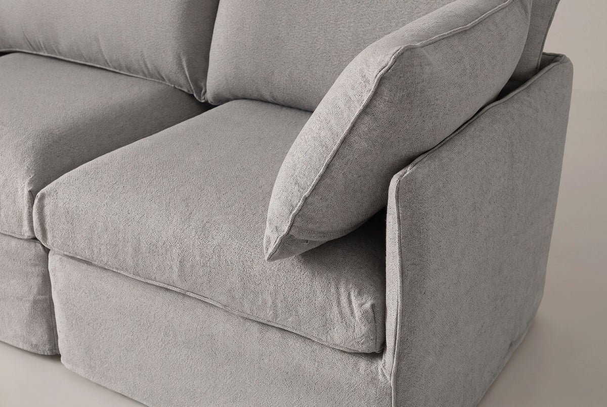 A Nicosia corner module up close: the low slim arm, the corner throw pillow, the seat cushion and the slipcover skirt