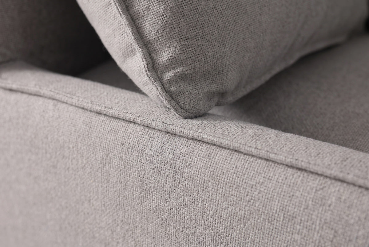 Close-up of the grey outdoor fabric on the Nicosia sofa: the woven texture, a cushion seam and the flange edge of a throw pillow