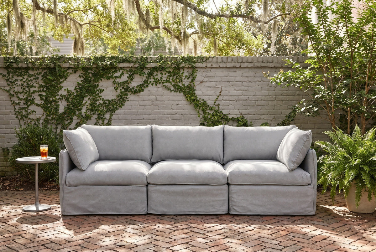 Nicosia grey slipcovered sofa in a walled Savannah courtyard with a grey brick wall, creeping fig and herringbone brick paving (side table not included)