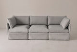 The Nicosia modular sofa from the front: three grey slipcovered seats, two low arms and two corner throw pillows