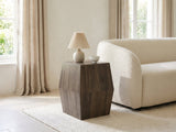 Nicotera Ash Grey Mango Faceted Side Table with a lamp and a ceramic bowl beside a cream boucle armchair in a bright plaster room