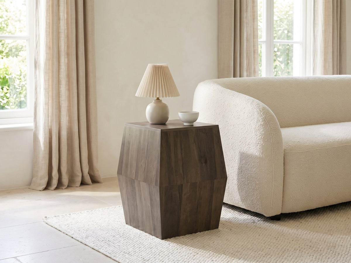Nicotera Ash Grey Mango Faceted Side Table with a lamp and a ceramic bowl beside a cream boucle armchair in a bright plaster room