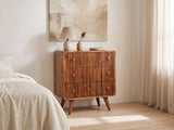 Noale 28-Inch Honey Caramel Solid Mango 3-Drawer Chest against a plaster wall under an abstract canvas in a bright bedroom