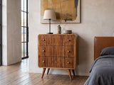Noale 28-Inch Honey Caramel Solid Mango 3-Drawer Chest against a plaster wall in an industrial loft bedroom