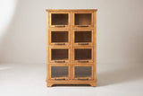 The Noci pine display cabinet in honey pine, front view on a light studio backdrop