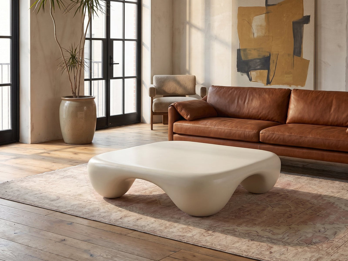 Noli White Sculpted Fiberglass Coffee Table on a vintage rug in front of a leather sofa in an industrial loft
