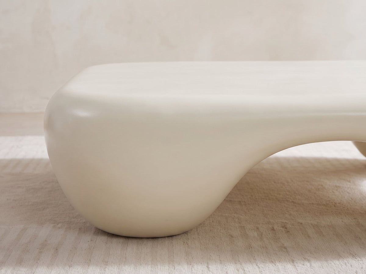 Close-up of the Noli White Sculpted Fiberglass Coffee Table: a rounded corner foot flowing down from the sculpted top