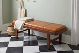 Norcia tan leather bench in a Charleston entry hall with a sage-green plaster wall, a black-and-white checkerboard marble floor, a folded linen throw and a seagrass basket