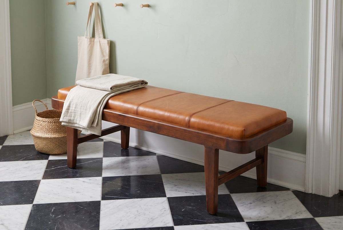 Norcia tan leather bench in a Charleston entry hall with a sage-green plaster wall, a black-and-white checkerboard marble floor, a folded linen throw and a seagrass basket