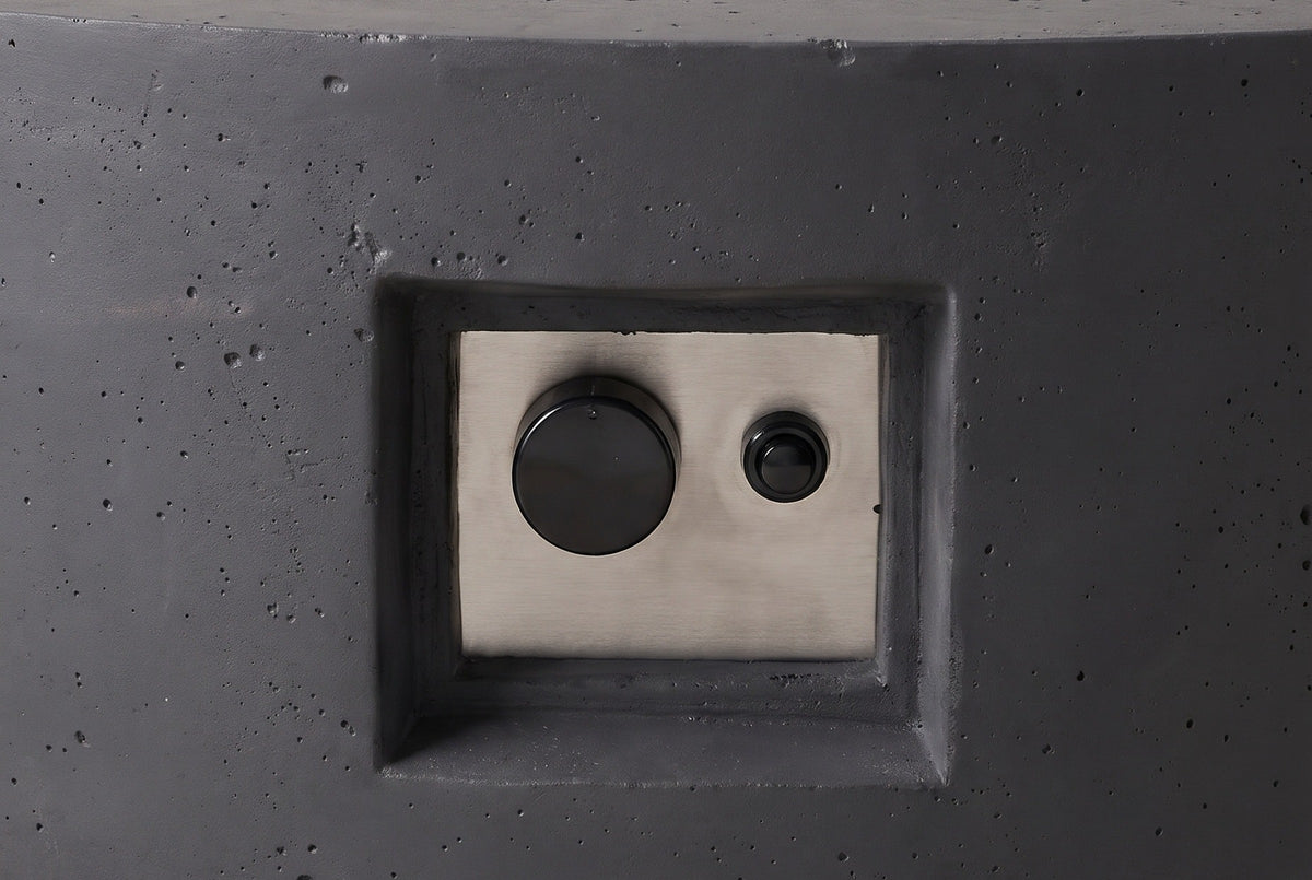 Close view of the Noto fire pit's control niche: a recessed niche in the concrete side wall with a brushed steel plate, one control knob and one push button