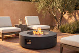 Noto fire pit lit on a terracotta-tiled garden terrace in Ojai, California at golden hour, a pink lime-plaster wall, an olive tree and lavender behind (chairs, side table and lantern not included)