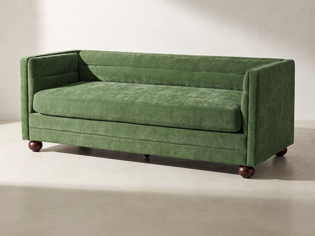 Novara Channel-Back Sofa in forest green against a plaster wall in morning light