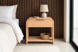 Nuoro Caramel Waterfall nightstand with a ceramic lamp and a seagrass basket against dark walnut slat panelling in a Palm Springs bedroom with a polished concrete floor and a wool rug