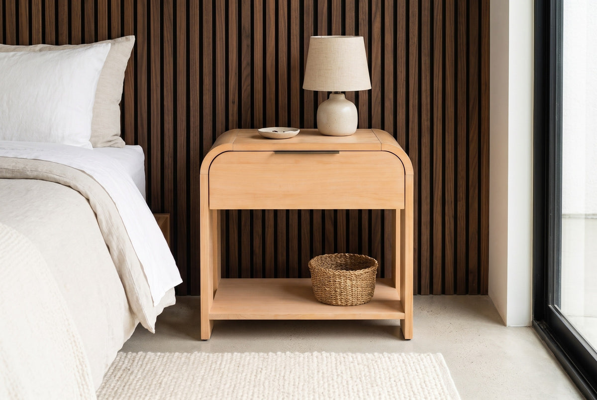Nuoro Caramel Waterfall nightstand with a ceramic lamp and a seagrass basket against dark walnut slat panelling in a Palm Springs bedroom with a polished concrete floor and a wool rug
