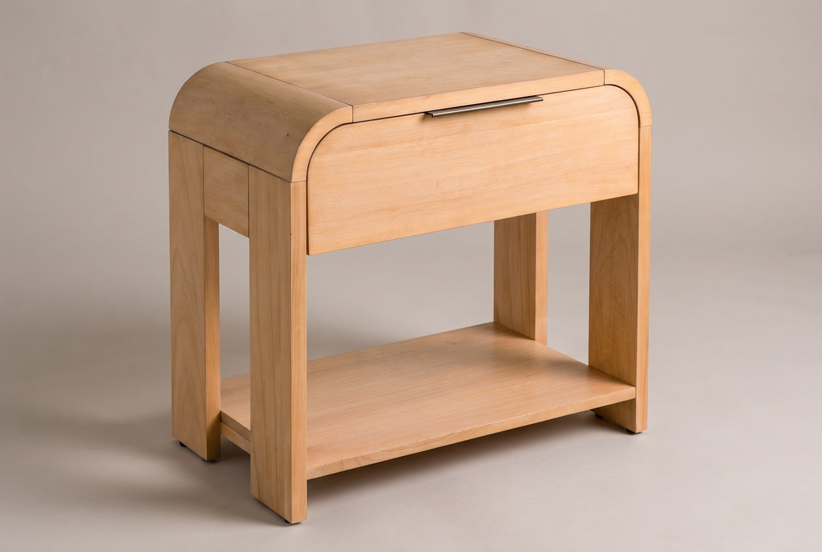 The Nuoro Caramel Waterfall nightstand with a waterfall top, one drawer with a slim bronze pull, four slab legs and an open lower shelf, three-quarter view on a warm grey studio backdrop