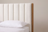 One side of the Ofena headboard: a slim round honey-finish post beside the plump white boucle channels, above a white pillow