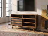 Offida Two-Tone Acacia Media Console seen from the side, under a wall-mounted screen in an industrial loft