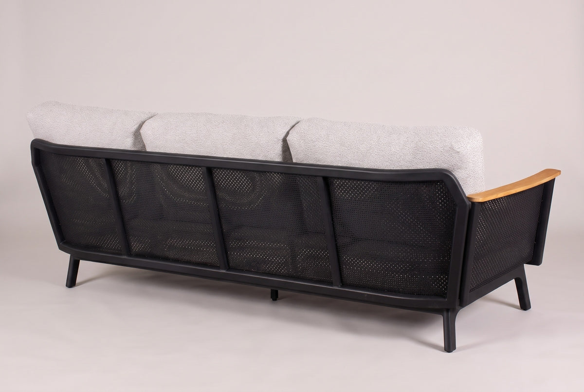 The Ognina sofa from behind: four black perforated mesh panels between slim posts, the three grey back cushions above the back rail