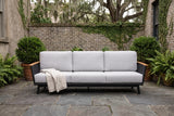 Ognina outdoor sofa in a Savannah courtyard on dark slate pavers, an old grey brick wall with creeping fig behind (throw not included)