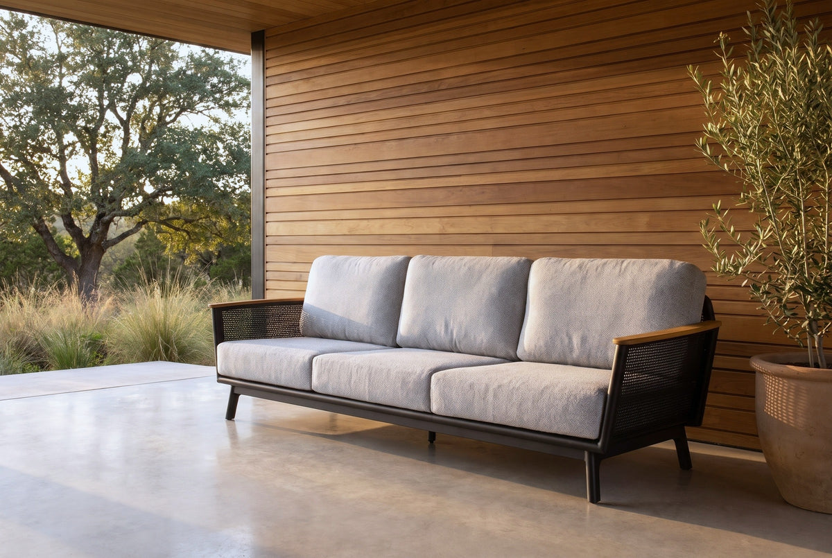 Ognina outdoor sofa on a polished concrete patio at a house in the Texas Hill Country near Austin, a cedar slat wall and live oaks behind (olive tree not included)